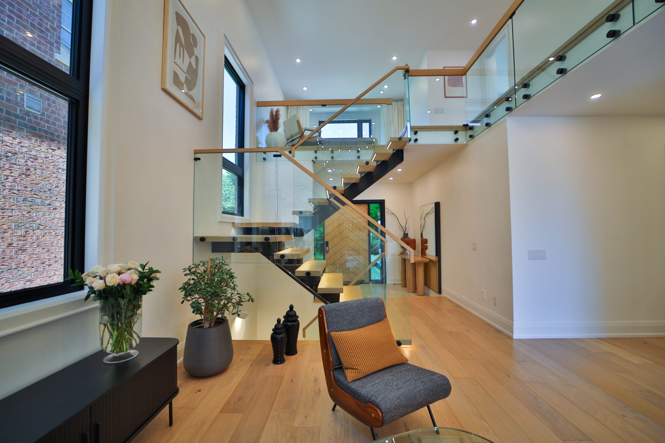 A whole home renovation showcasing the foyer featuring a large front door, windows, seating area and staircase.