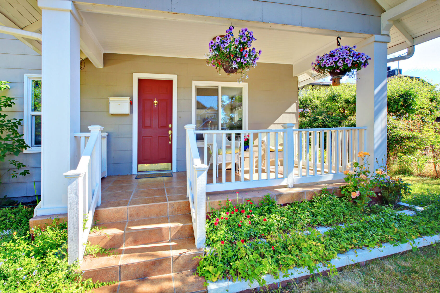 Charming house entrance with red door and flower-filled porch