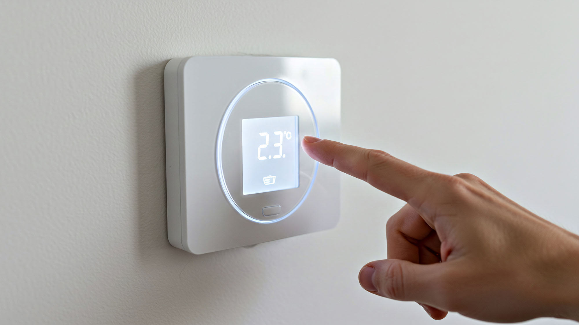 A hand adjusts a modern smart thermostat, highlighting the concept of home automation. Concept of climate control and home automation.
