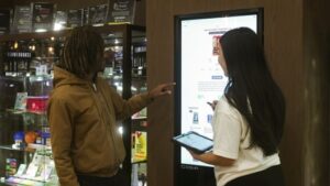 Two people using a touch screen kiosk in a retail store