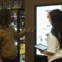 Two people using a touch screen kiosk in a retail store