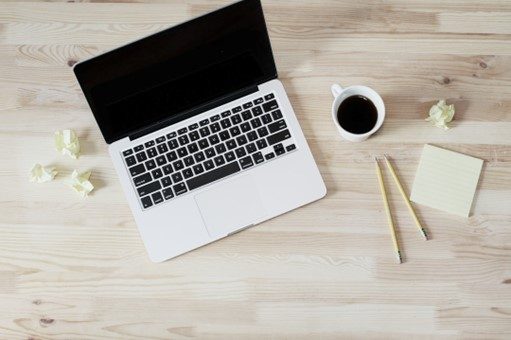 Laptop with coffee and pencils on wooden table.