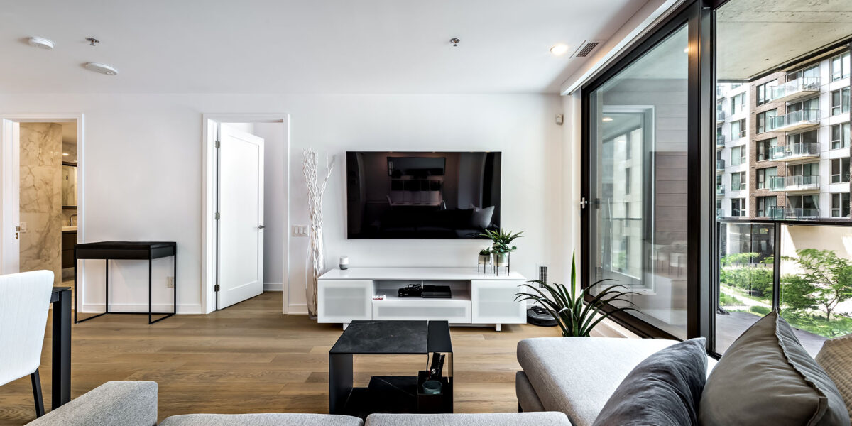 Modern condo living room with TV and city view balcony