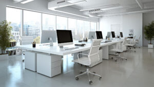 Modern open-plan office interior with sleek white desks and large windows