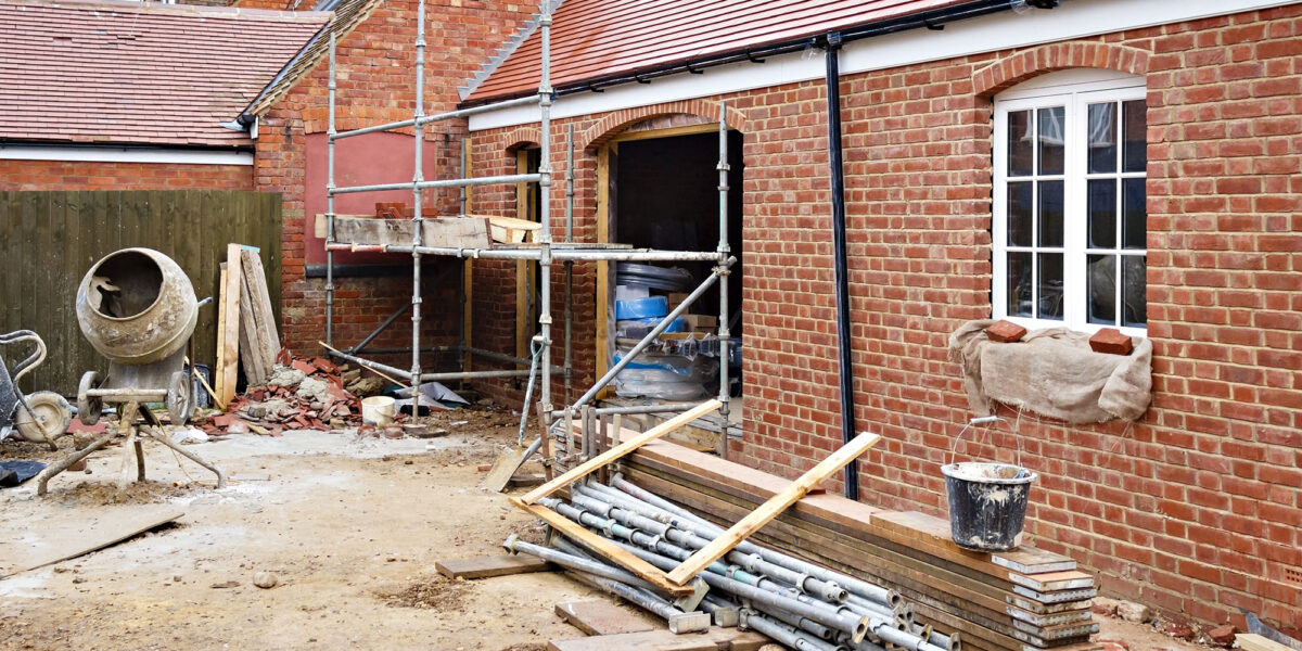Residential brick house construction site with scaffolding and building materials