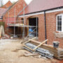Residential brick house construction site with scaffolding and building materials