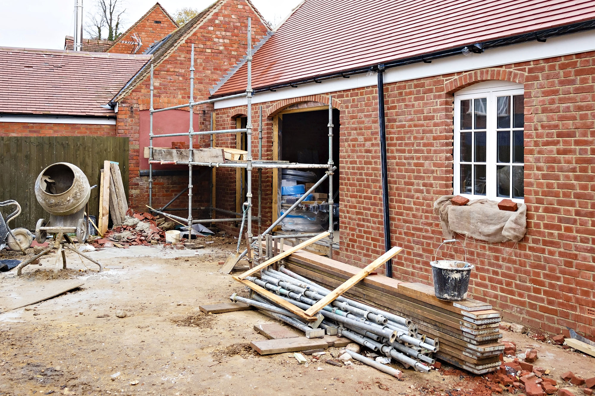 Residential brick house construction site with scaffolding and building materials