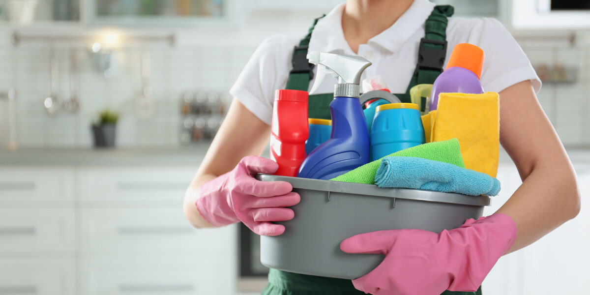 Person holding cleaning supplies in a modern kitchen