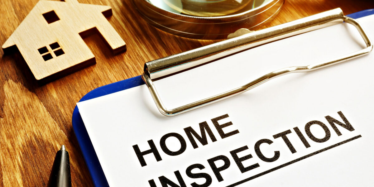 Home inspection checklist with house model on wooden desk