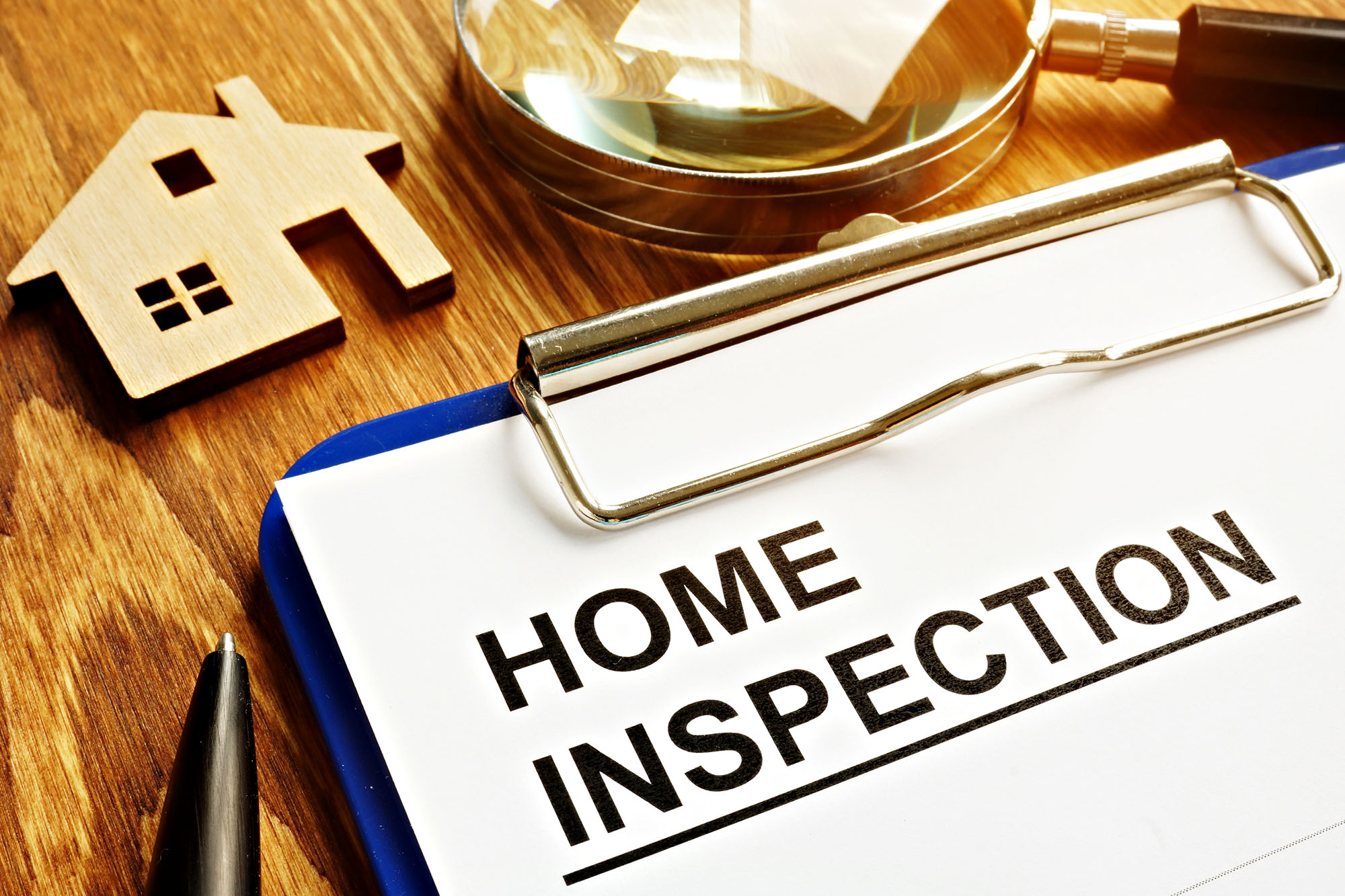 Home inspection checklist with house model on wooden desk