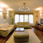 Modern living room with beige sofas, wooden floor, and large window