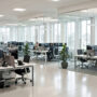 Modern open-plan office with employees working at desks and glass partitions