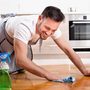 Man smiling while cleaning wooden floor with spray and cloth