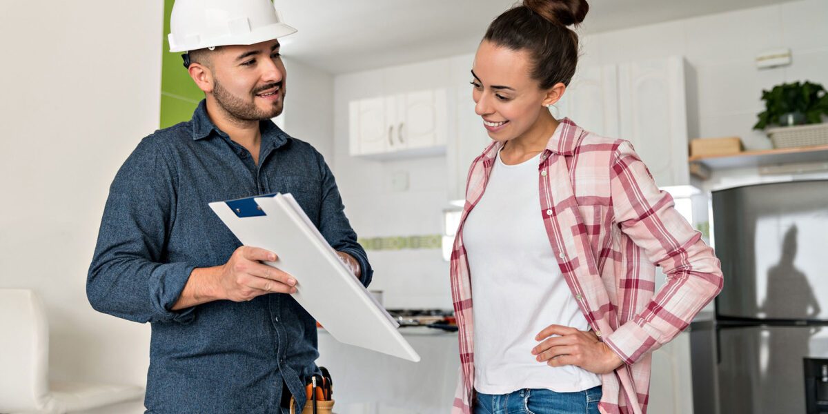 Architect talking to a woman about remodeling her house and showing her the blueprints - home addition concepts