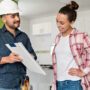 Architect talking to a woman about remodeling her house and showing her the blueprints - home addition concepts