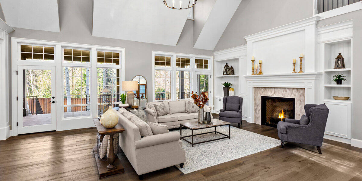 Beautiful living room in new traditional style luxury home. Features vaulted ceilings, fireplace with roaring fire, and elegant furnishings.