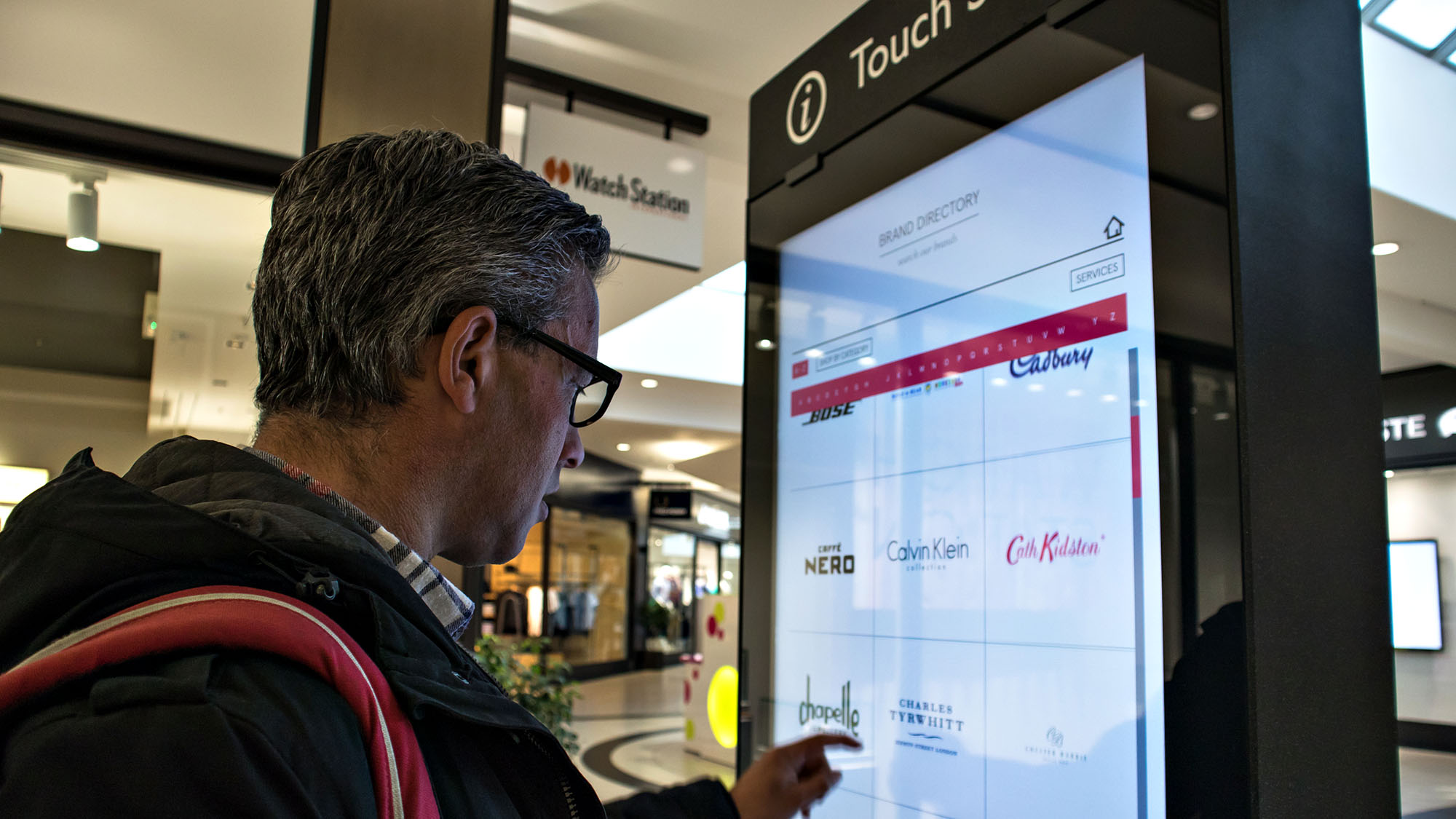 Man using a touch screen directory in shopping mall