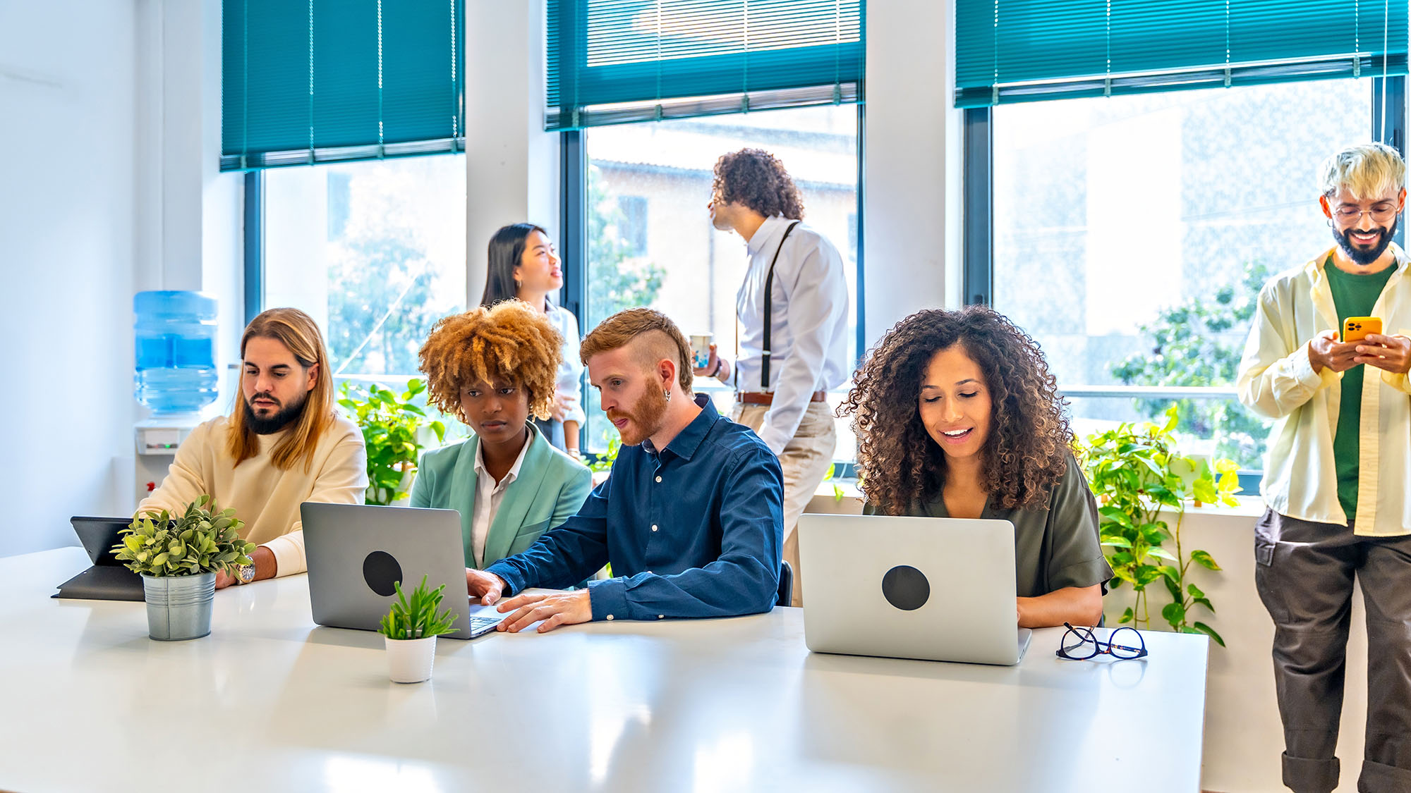Diverse team collaborating at office with laptops and discussion