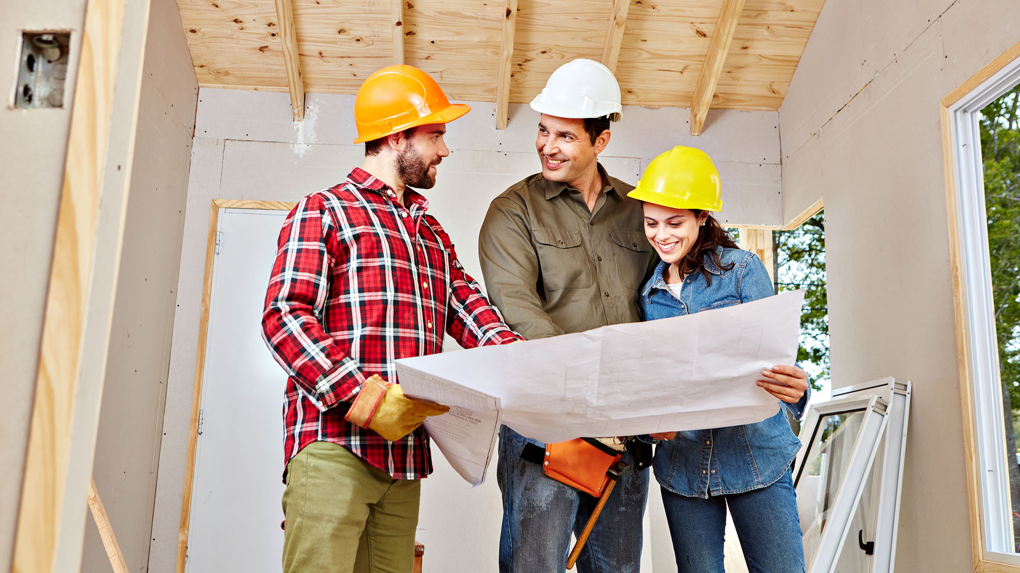 Construction team reviewing architectural plans inside a building site