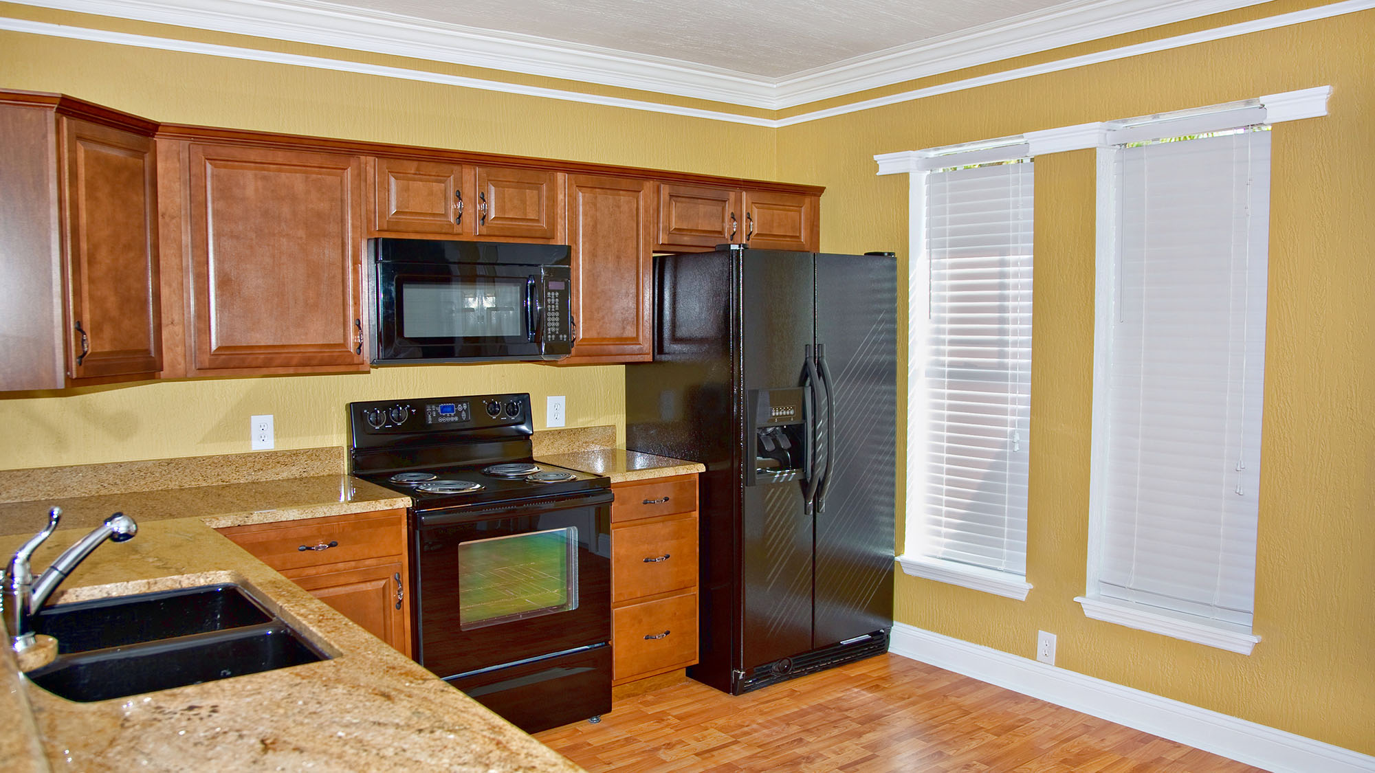 Modern kitchen with wooden cabinets, black appliances, and granite countertops