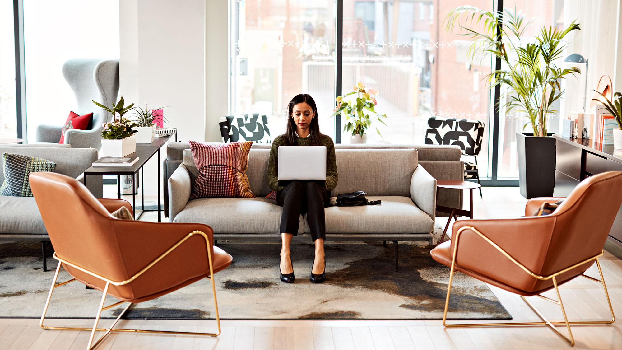 Modern coworking space with stylish furniture and a focused professional on laptop