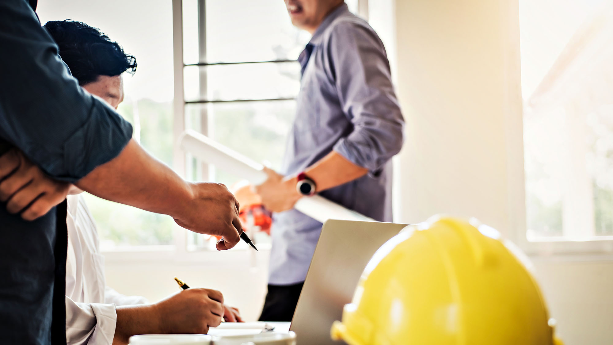 Group of professionals discussing construction project with laptop and safety helmet