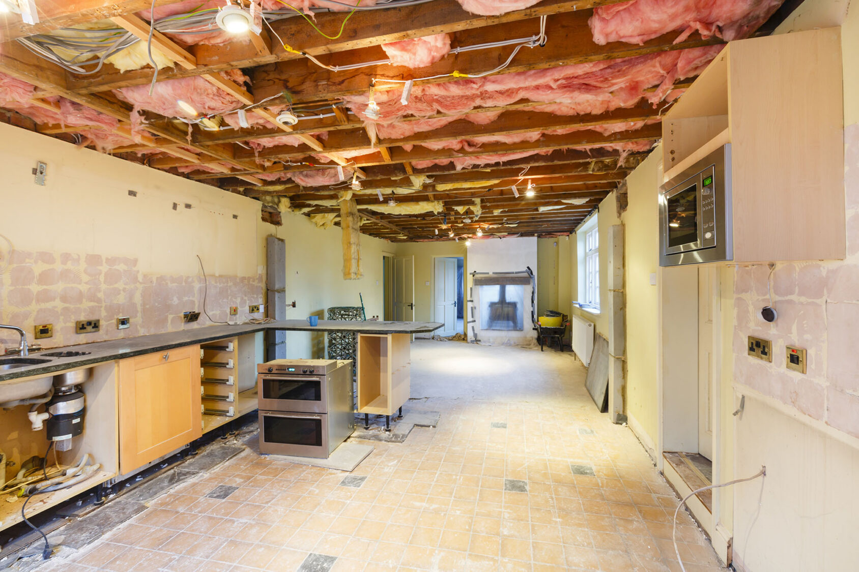Home kitchen under renovation with exposed ceiling and partially installed cabinets