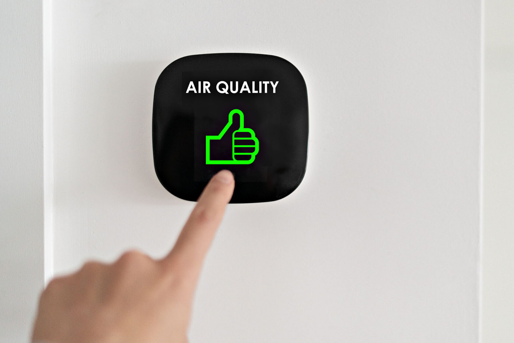 Person interacting with air quality monitor showing positive rating