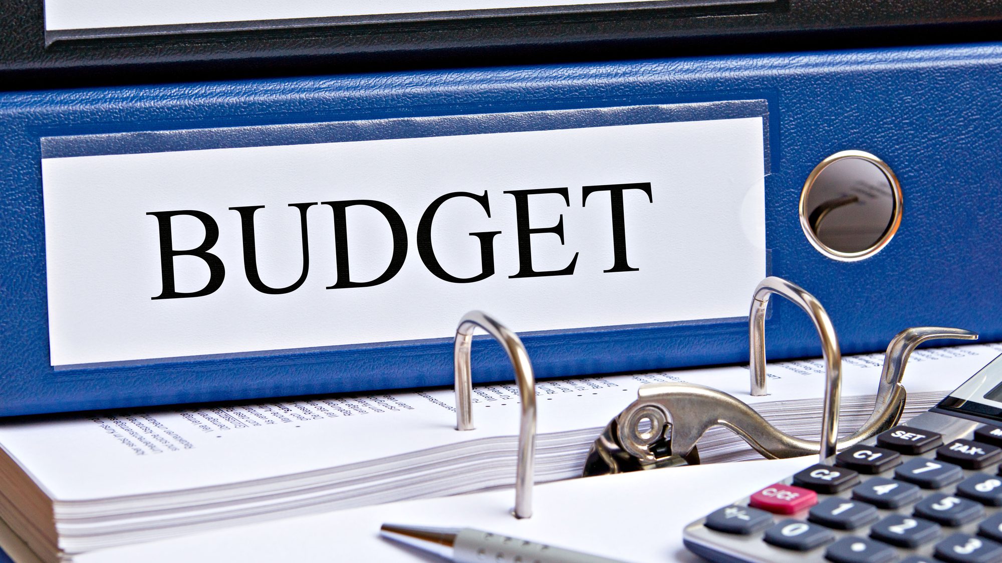 Blue binder labeled Budget with calculator and papers