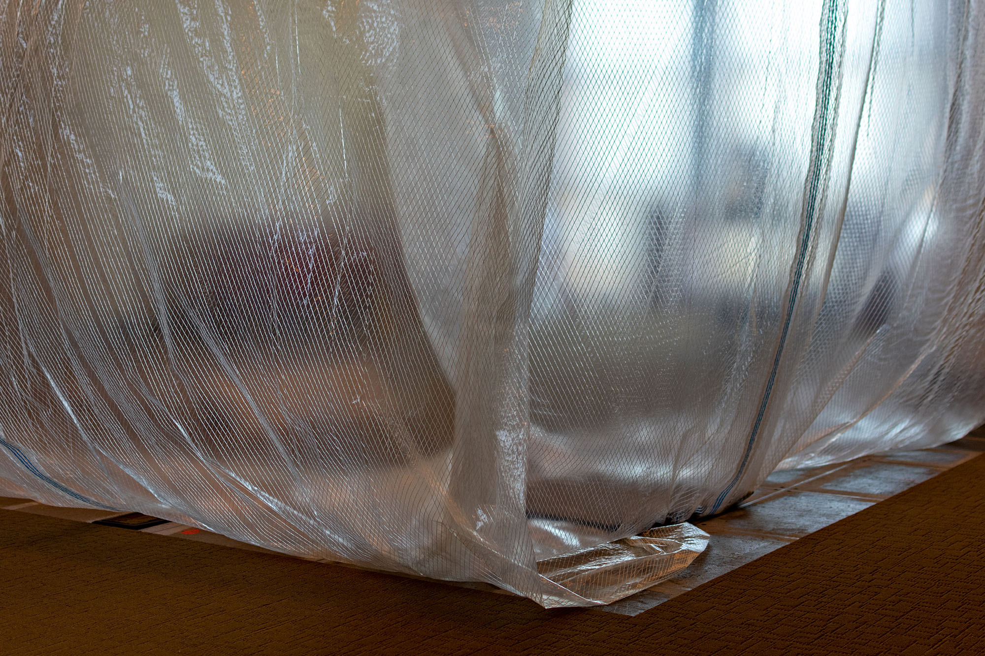 Plastic sheet gently draped and secured to a floor surface