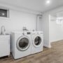 Renovated basement laundry space with white appliances