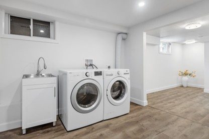 Renovated basement laundry space with white appliances