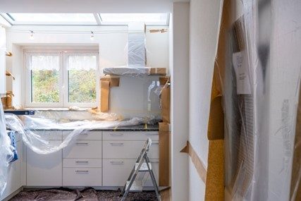 White kitchen undergoing renovations with plastic covering counter.