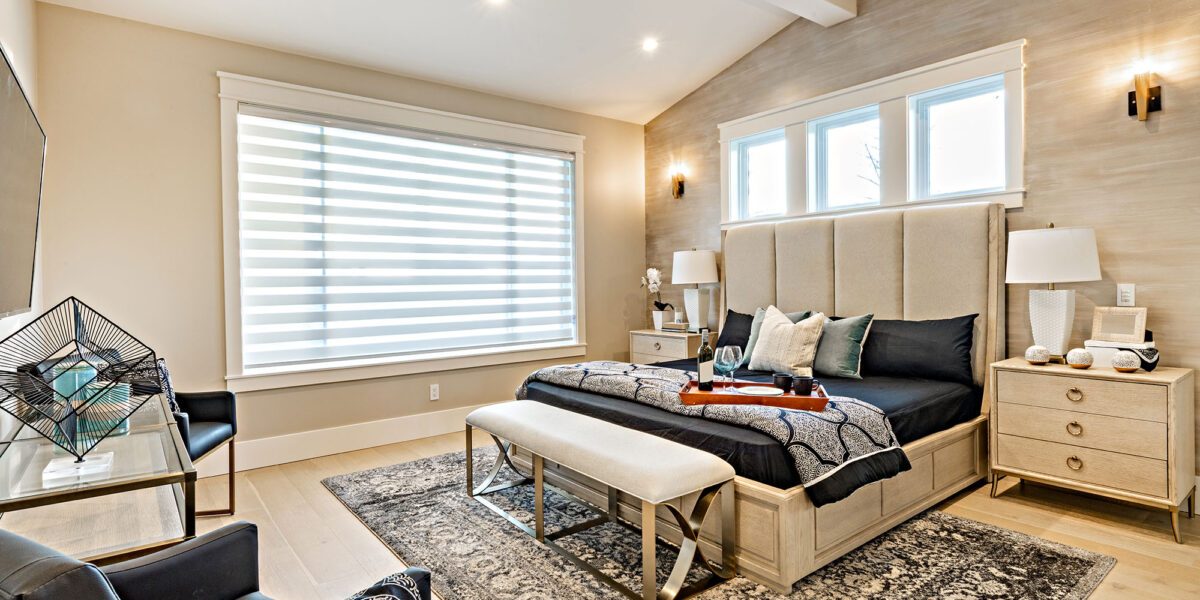 master bedroom with large windows black linens staged with wine and glasses