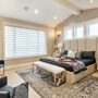 master bedroom with large windows black linens staged with wine and glasses