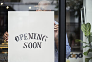 Storefront with 'Opening Soon' sign held by a person