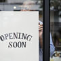 Storefront with 'Opening Soon' sign held by a person