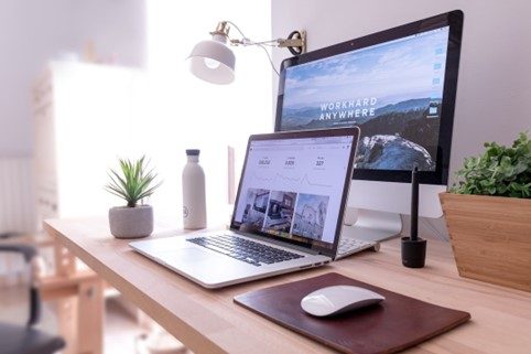 Desktop workspace with large monitor and laptop.