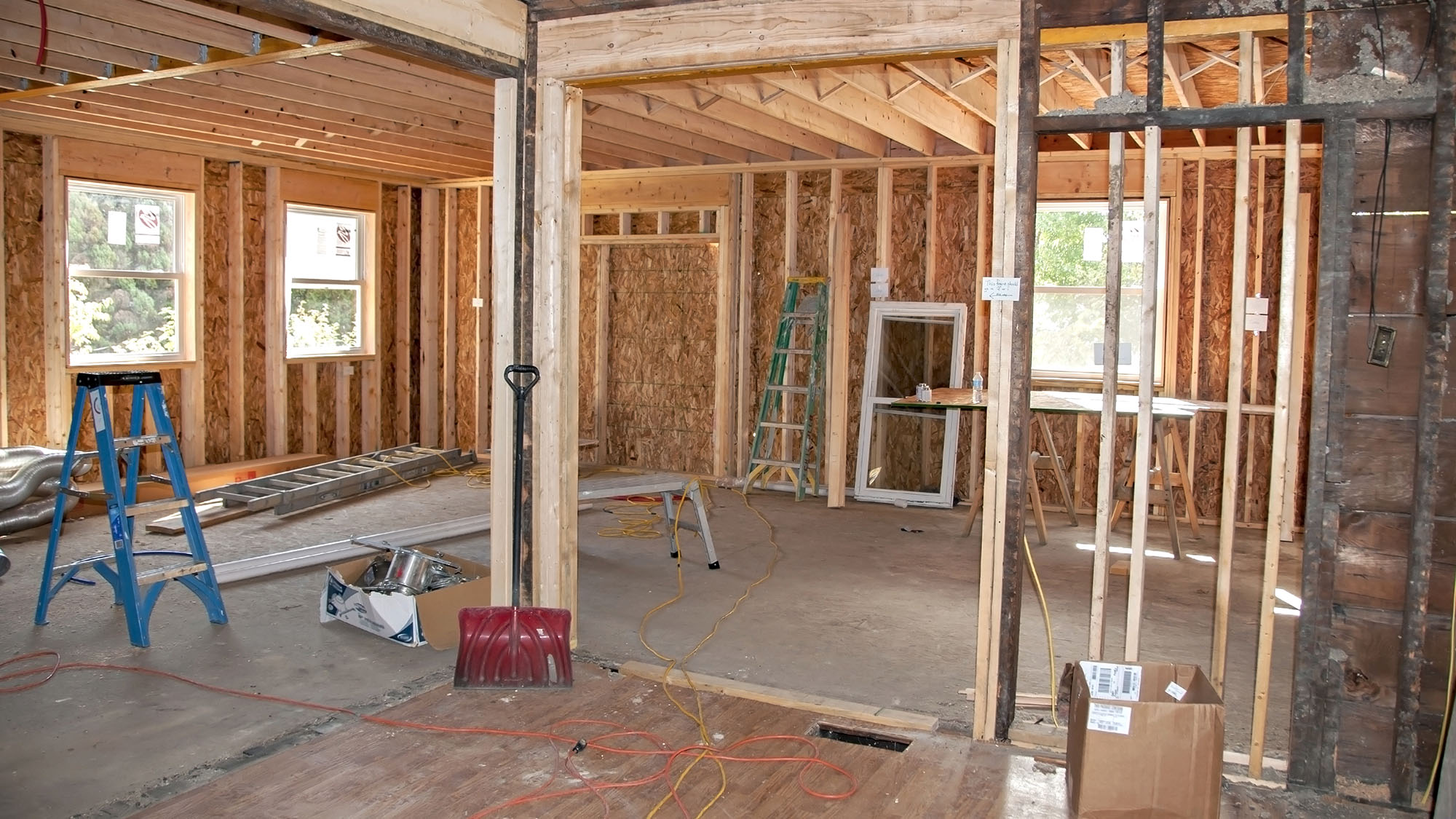 Home renovation construction site with exposed wooden framing and tools