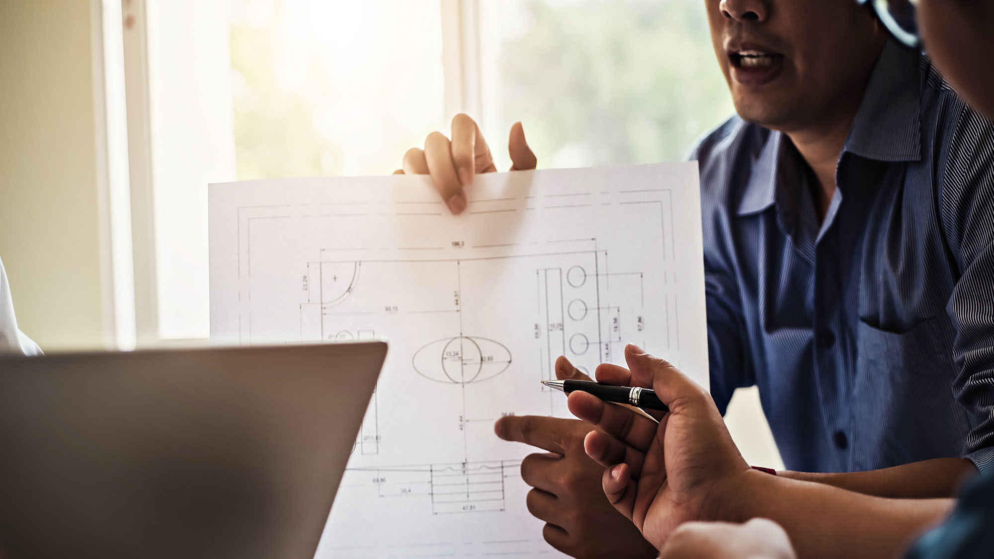 Architects collaborating on construction blueprint in office meeting