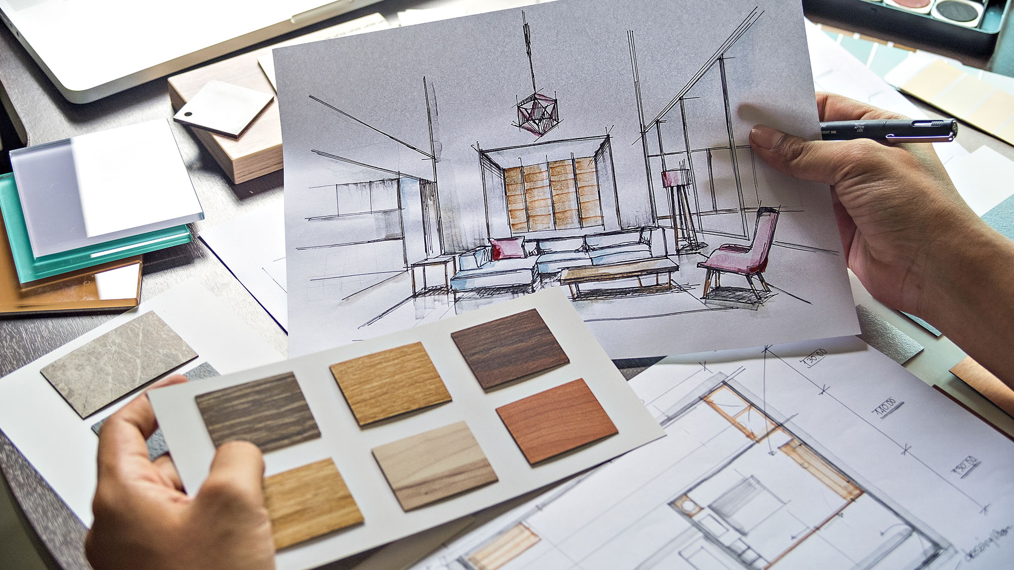 Architect holding interior design sketch with wood samples on desk