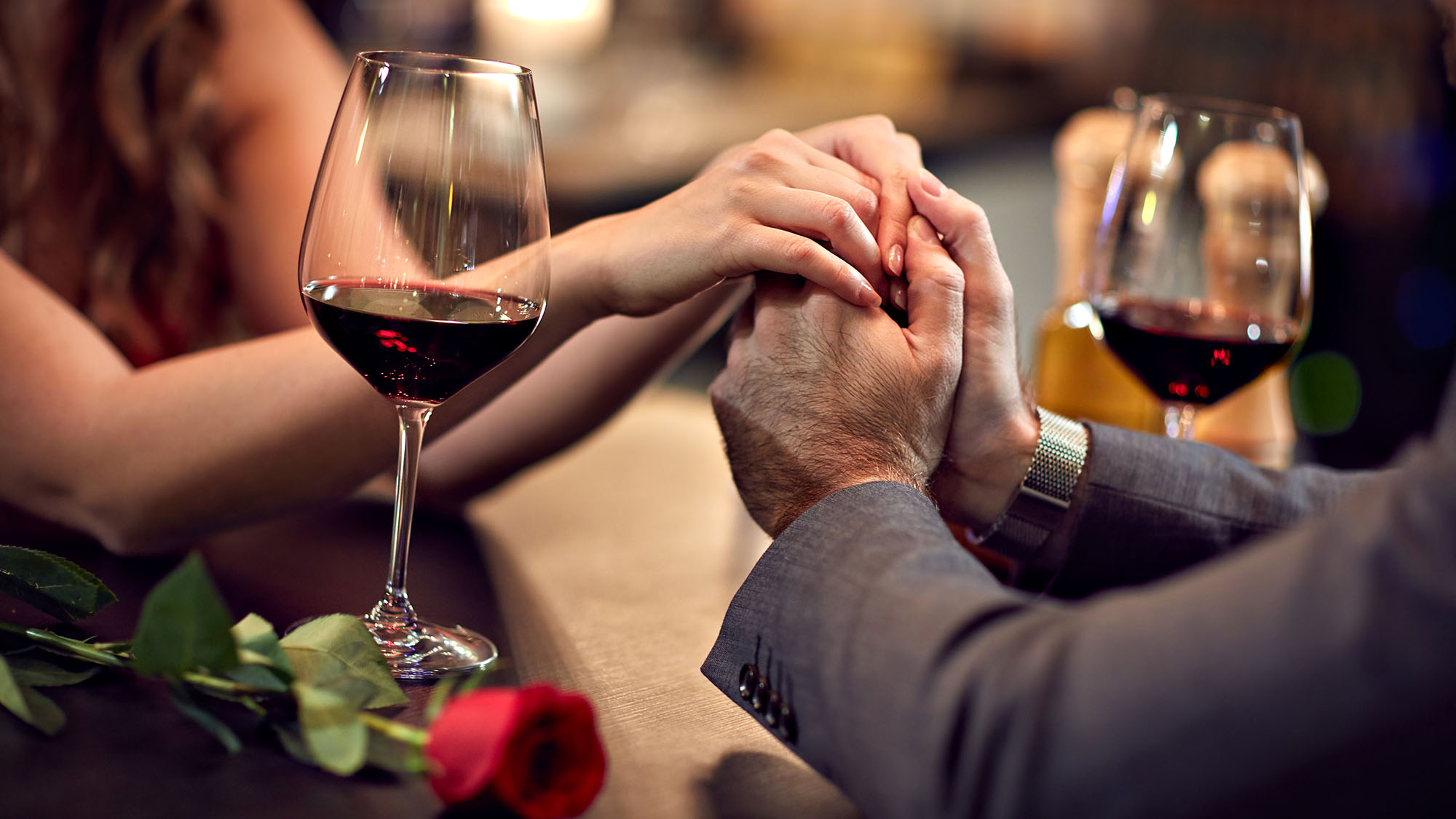 Couple holding hands over wine glasses on a romantic date