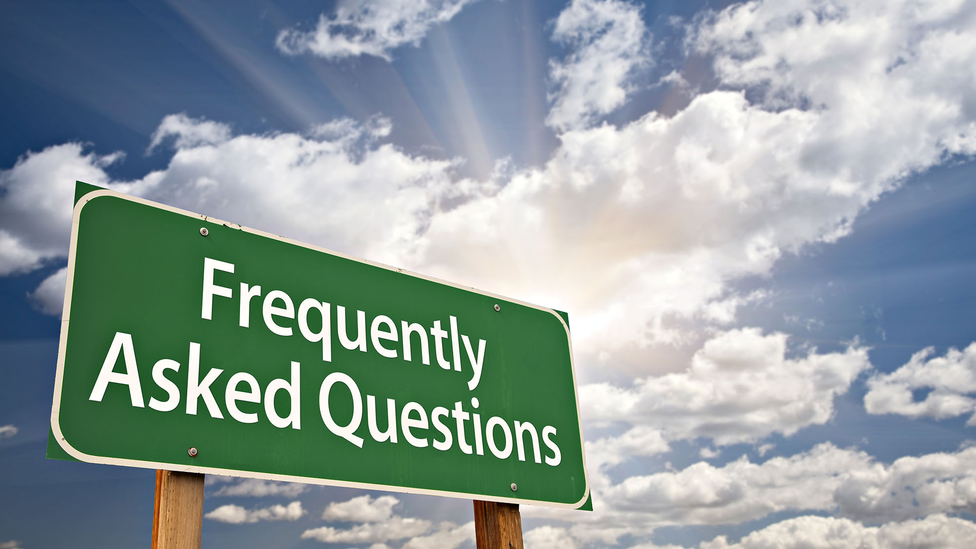 Green FAQ sign under a sunny sky with scattered clouds
