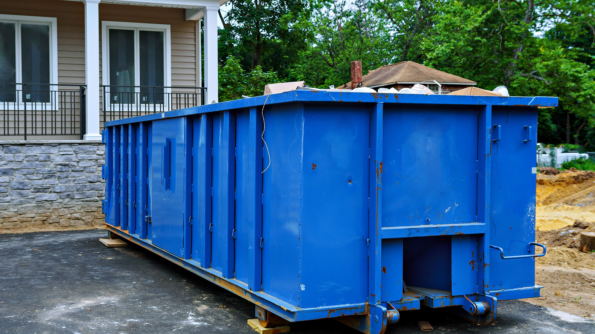 Large blue dumpster outside residential building during renovation